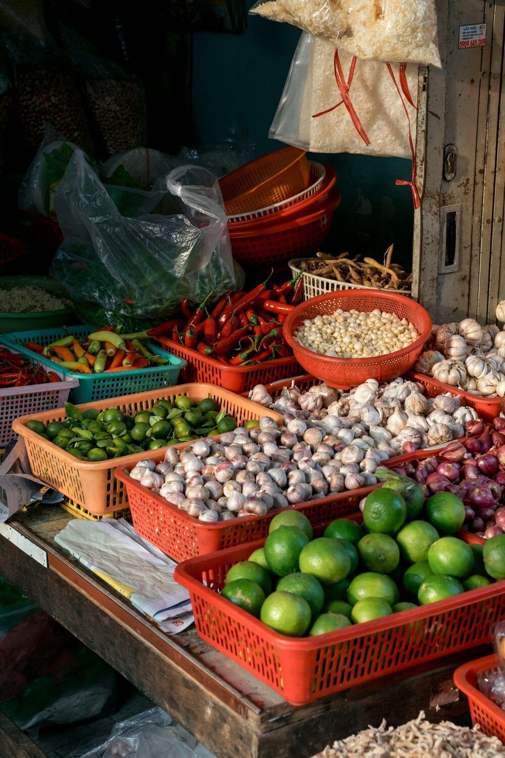 Limes, garlic, shallots and chillies in plastic baskets at a Saigon market stall